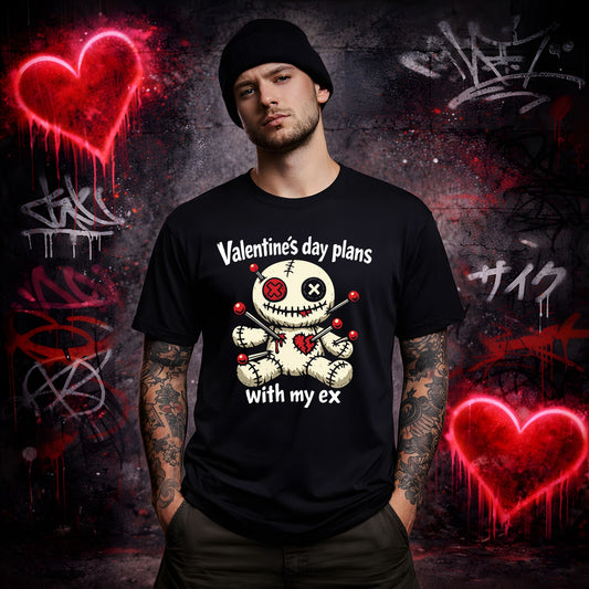 Man wearing a black t-shirt with a graphic design and text, standing against a graffiti-covered wall with red hearts.