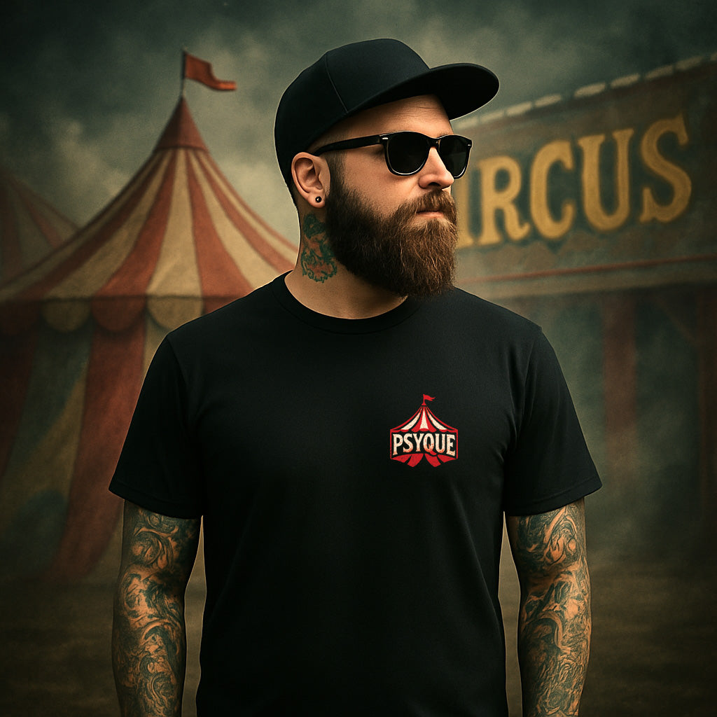 Man wearing a black t-shirt with a logo in front of a circus tent.