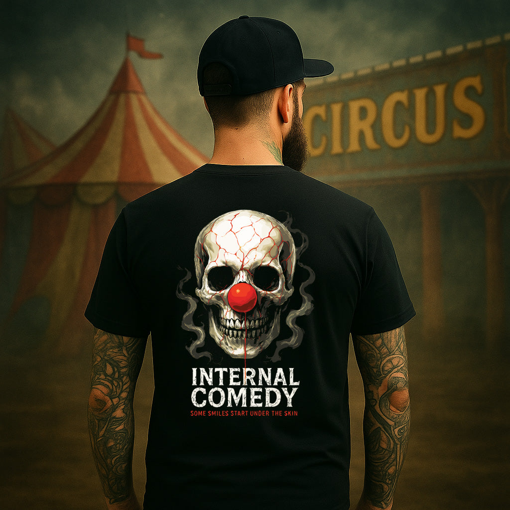 Person wearing a black t-shirt with a skull and clown nose design, standing in front of a circus tent.