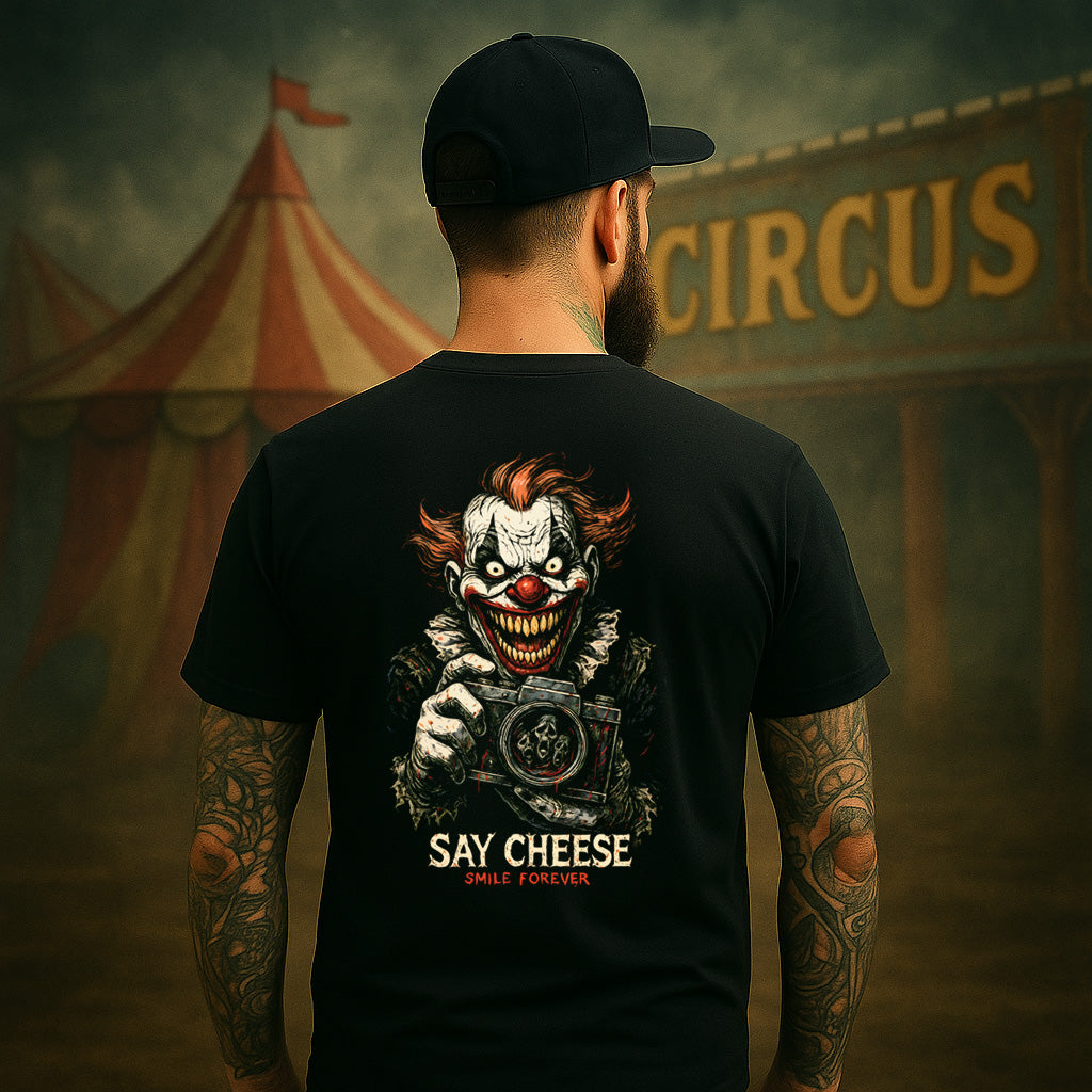Person wearing a black t-shirt with a clown graphic and 'Say Cheese' text, standing in front of a circus tent.